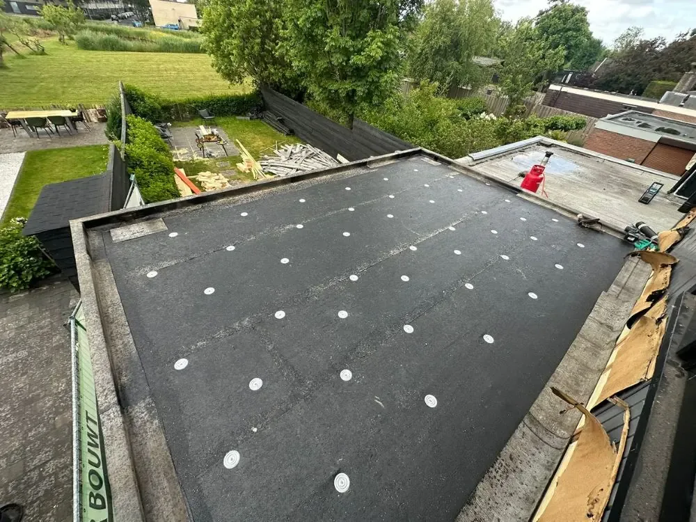 Eerste laag dakbedekking met bevestigingsplaatjes op een plat dak in Heemskerk