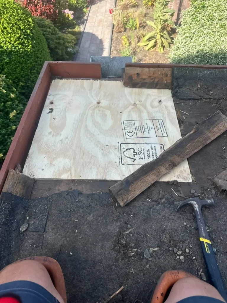 Nieuwe multiplexplaat in het dakbeschot van een plat dak, met een hamer ernaast in Velsen