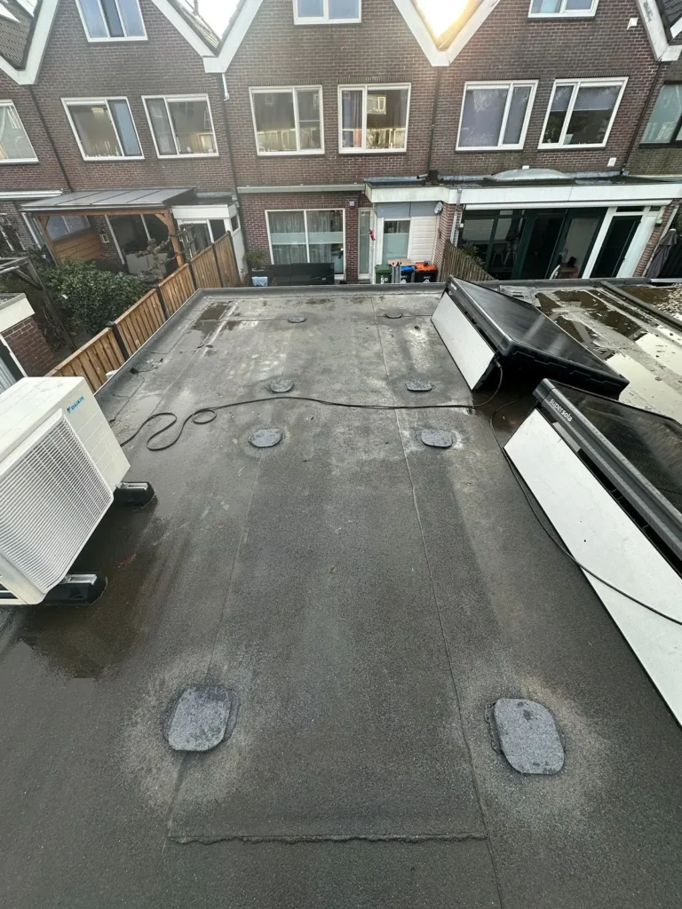 Plat dak met nieuwe stukken bitumen op de plekken van de zonnepaneelsteunen in Westzaan