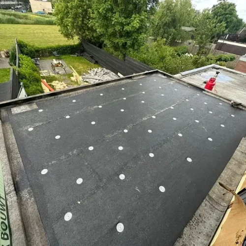 Eerste laag dakbedekking met bevestigingsplaatjes op een plat dak in Akersloot