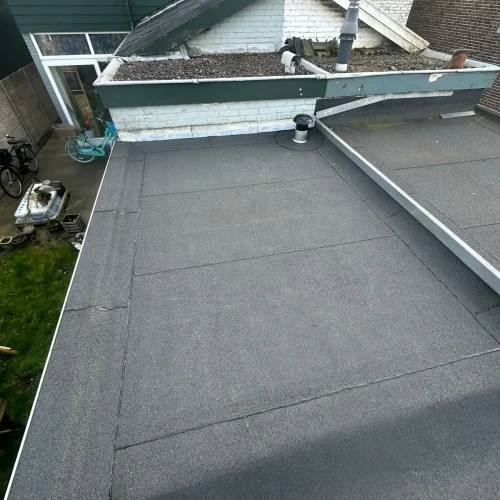 Nieuw bitumen dak met dakrandprofiel boven een achtertuin in Beverwijk