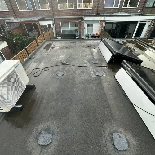 Plat dak met nieuwe stukken bitumen op de plekken van de zonnepaneelsteunen in Uitgeest