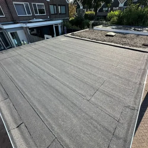 Nieuwe bitumen dakbedekking op een plat dak achter een woning in Wormer