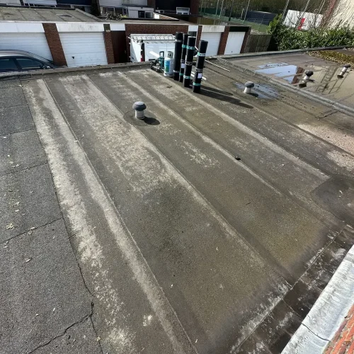 Oud plat garagedak met rollen bitumen, garageboxen op de achtergrond in Wormer