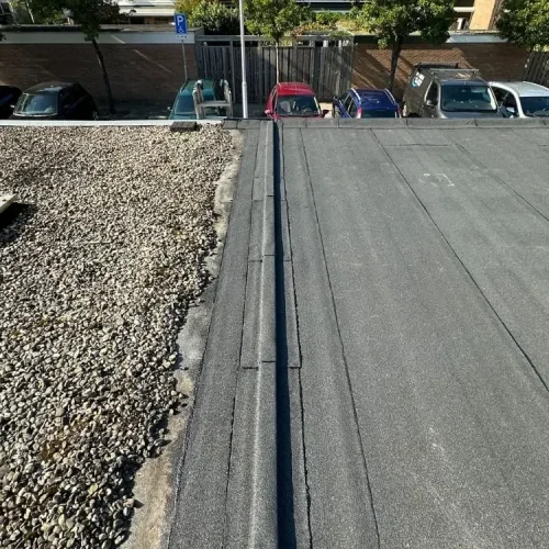 Nieuwe bitumen dakbedekking die aansluit op een grinddak met lichtkoepel in Zandvoort
